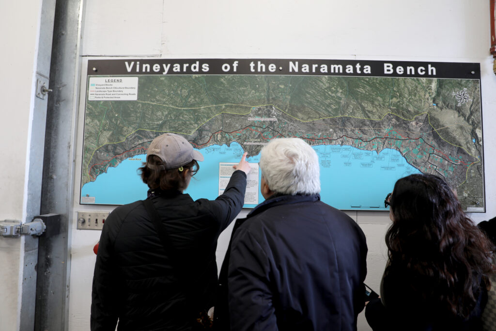 Three people looking at a map of the vineyards of Naramata Bench